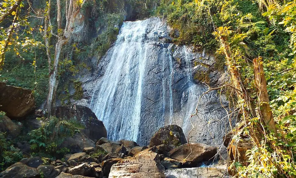 Sunlit waterfall cascading through El Yunque rainforest
